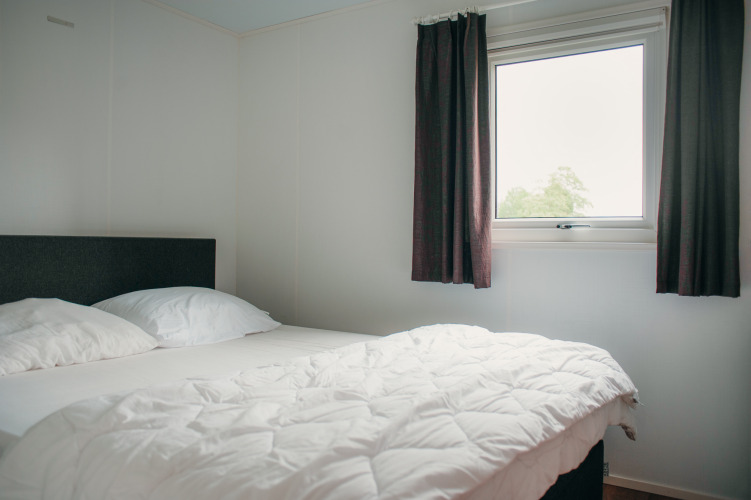 Dormitorio en Veluwelodge en el parque vacacional De Boshoek, Países Bajos, con cama y ventana con cortinas.