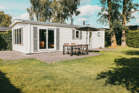 Außenansicht der Veluwe Lodge mit Terrasse, Gartenmöbeln und Sonnenschirm im Ferienpark De Boshoek.
