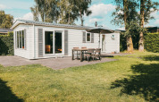 Vista exterior de la Veluwe lodge con terraza, mesa y sillas al aire libre en Holiday park De Boshoek.