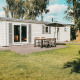 Buitenaanzicht van Veluwe lodge met terras, tuinset en parasol bij Holiday park De Boshoek in Nederland.