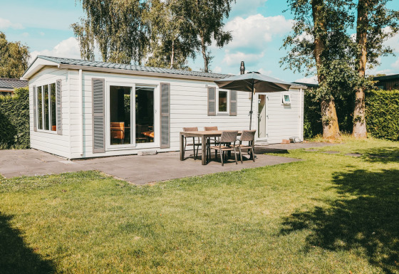 Vue extérieure de la Veluwe lodge avec terrasse, meubles de jardin et parasol au Holiday park De Boshoek.