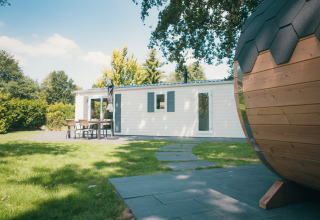 Vista exterior de Veluwe lodge con sauna en Holiday park De Boshoek, Países Bajos, con jardín y terraza.