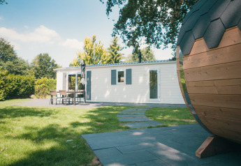 Vista exterior de Veluwe lodge con sauna en Holiday park De Boshoek, Países Bajos, con jardín y terraza.