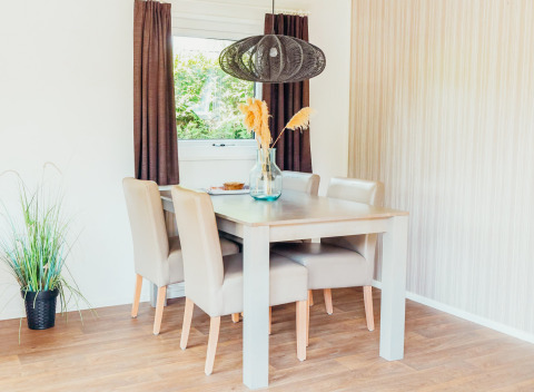 Licht eetgedeelte in Veluwe lodge + sauna op Holiday park De Boshoek, Nederland, met moderne meubels.