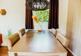Comedor de Veluwe lodge con mesa de madera, cuatro sillas y ventana con vista natural en De Boshoek, Países Bajos.