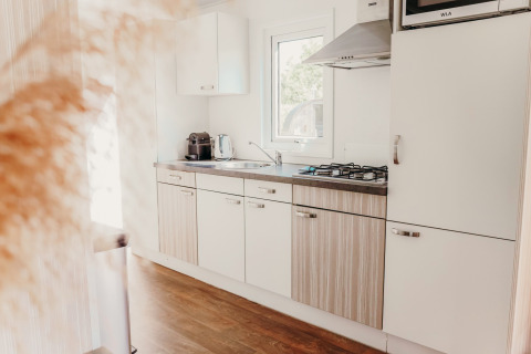 Lichte, moderne keuken met houten vloer en gaskookplaat in Veluwe lodge op De Boshoek vakantiepark.