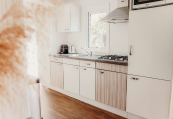 Lyst og moderne køkken i en Veluwe lodge med trægulv, gaskomfur og vindue, De Boshoek, Holland.