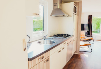 Moderne keuken in Veluwe lodge + sauna bij Holiday park De Boshoek, Nederland, met zicht op de woonkamer.