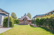 Foto af en træhytte og grønne omgivelser på Veluwelodge XL, feriepark De Boshoek, Holland.
