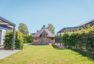 Foto af en træhytte og grønne omgivelser på Veluwelodge XL, feriepark De Boshoek, Holland.