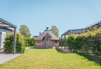 Foto af en træhytte og grønne omgivelser på Veluwelodge XL, feriepark De Boshoek, Holland.
