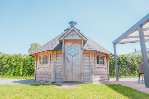 Foto de Veluwelodge XL en Holiday park De Boshoek en los Países Bajos, una acogedora cabaña de madera al sol.