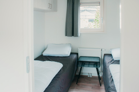 Kamer met twee eenpersoonsbedden, raam en tafeltje in Veluwelodge XL, Vakantiepark De Boshoek, Nederland.