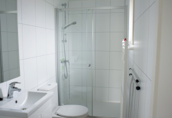 Modern bathroom with shower, sink and toilet inside Veluwelodge XL at Holiday park De Boshoek in the Netherlands.