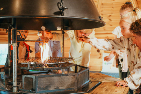 Kinder rösten Marshmallows am Lagerfeuer in der Veluwelodge XL im Ferienpark De Boshoek, Niederlande.