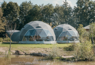 Dos tiendas redondas de glamping junto a un estanque en Holiday Park Sallandshoeve, Países Bajos, rodeadas de naturaleza.
