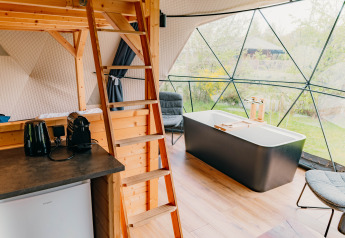 Indvendig af Round Holly Tent i Holiday Park Sallandshoeve med badekar, sofa og moderne interiør.