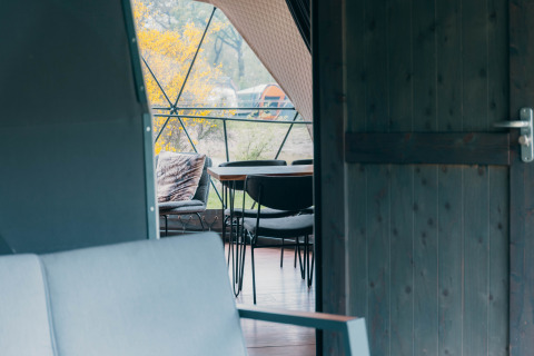 Blick durch eine offene Tür auf eine Terrasse mit Sitzplätzen im Round Holly Tent, Holiday Park Sallandshoeve, Niederlande.