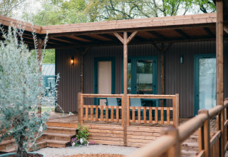 Moderna cabaña Luxury Lodge con terraza y baranda de madera, rodeada de vegetación exuberante y tranquila.