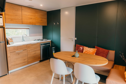 Moderne Küche und Essbereich in der Luxury Lodge, mit Holzmöbeln, grüner Wand und gemütlicher Sitzbank.