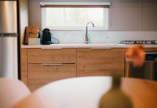 Cocina moderna en Luxury Lodge con gabinetes de madera, cafetera, estufa de gas y ventana grande.