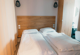 Habitación con dos camas individuales, ropa de cama blanca y cabecero de madera en Luxury Lodge.