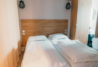 Habitación con dos camas individuales, ropa de cama blanca y cabecero de madera en Luxury Lodge.