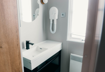 Moderne badeværelse på Luxury Lodge med sort vandhane, spejl, hårtørrer og vindue med lysindfald.
