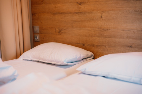 Habitación acogedora en Luxury Lodge con dos camas individuales, almohadas blancas y panel de madera detrás.