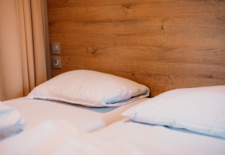 Habitación acogedora en Luxury Lodge con dos camas individuales, almohadas blancas y panel de madera detrás.