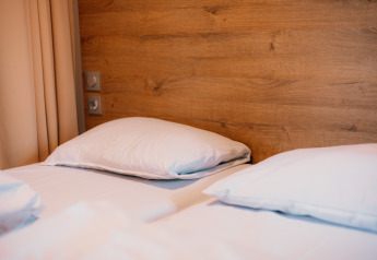 Et hyggeligt værelse på Luxury Lodge med to komfortable senge, hvide puder og træpaneler på væggen.