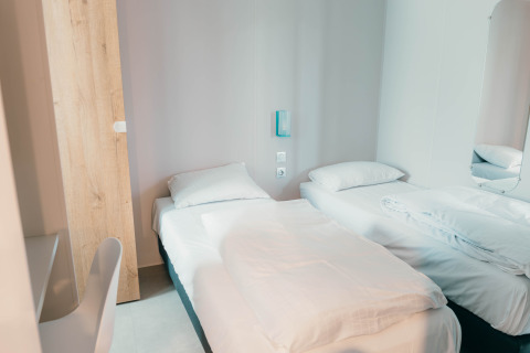 Habitación luminosa y moderna en Luxury Lodge con dos camas individuales, sábanas blancas y estilo minimalista.