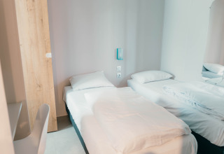 Habitación luminosa y moderna en Luxury Lodge con dos camas individuales, sábanas blancas y estilo minimalista.