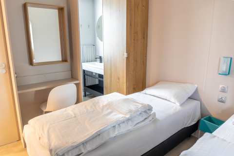 Heldere kamer in Luxury Lodge met een eenpersoonsbed, bureau, spiegel en toegang tot moderne badkamer.