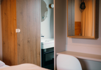 Chambre moderne à Luxury Lodge avec armoire en bois, bureau, miroir mural et vue sur la salle de bain.