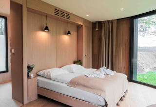 Acogedor dormitorio moderno en Lumni Pod, Wilsumer Berge, Alemania, con grandes ventanales y decoración de madera.