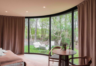 Vista desde la tiny house Lumni Pod en Wilsumer Berge, Alemania, con grandes ventanales y bosque.