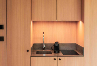 Pequeña cocina de madera con fregadero, cafetera y placa de cocción en la Lumni Pod de Wilsumer Berge.