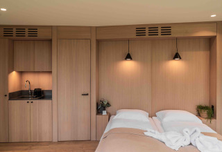 Interior moderno de la tiny house Lumni Pod en Wilsumer Berge, Alemania, con cama doble y pequeña cocina.