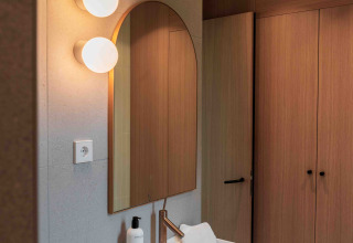 Baño moderno en Lumni Pod, Wilsumer Berge, con lavabo en la pared, espejo y armarios de madera.