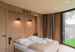 Dormitorio moderno con paneles de madera y grandes ventanales en Lumni Pod en Wilsumer Berge, Alemania.