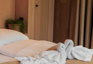 Cama en la tiny house Lumni Pod en Wilsumer Berge, Alemania, con animal decorativo de toalla sobre la manta.