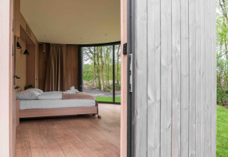 Entrada a la tiny house Lumni Pod en Wilsumer Berge, Alemania, con vista al dormitorio y naturaleza exterior.