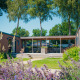 Vista soleada de la Family Lodge en el parque vacacional De Boshoek, Países Bajos, con terraza y vegetación.