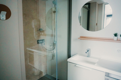 Bagno moderno con doccia, specchio rotondo, lavabo e pianta a Family Lodge, Holiday park De Boshoek, Paesi Bassi.