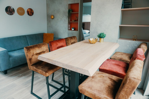 Sala de estar en Family Lodge de Holiday park De Boshoek, con mesa de madera y sillas cómodas y sofá azul.
