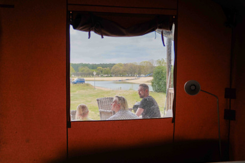 Vista desde el interior de una tienda safari en Wilsumer Berge, Alemania, con familia, lago y naturaleza.