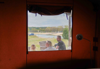 Vista desde el interior de una tienda safari en Wilsumer Berge, Alemania, con familia, lago y naturaleza.