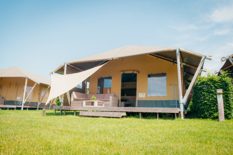 Cabaña safari con terraza y toldo en Holiday park De Boshoek, Países Bajos, en un día soleado.