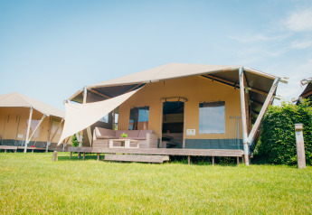 Cabaña safari con terraza y toldo en Holiday park De Boshoek, Países Bajos, en un día soleado.